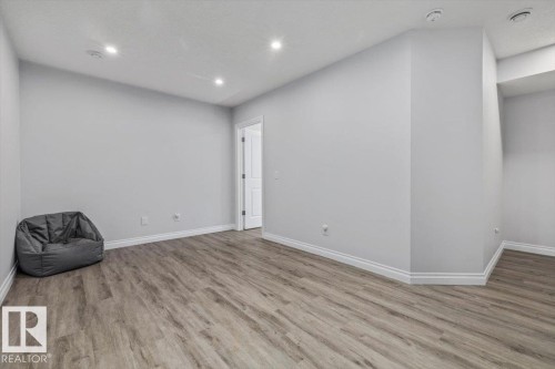 Recessed lighting, wood-finish flooring, white trim, and a paneled interior door - 1014 Daniels Loop Sw, Edmonton, AB - Indoor Photo Showing Other Room