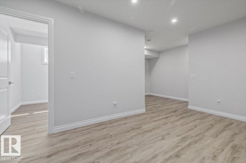 Contemporary interior with light gray walls, wood-finish flooring, recessed lighting, and white trim - 1014 Daniels Loop Sw, Edmonton, AB - Indoor Photo Showing Other Room