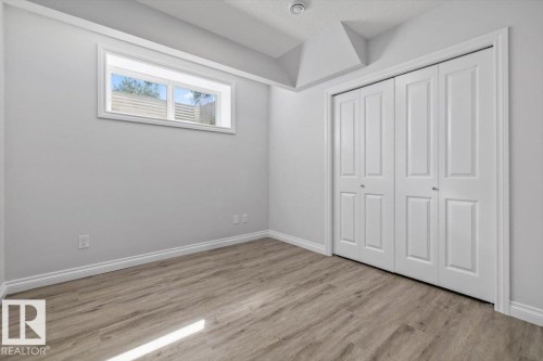 Neutral wall tones, wood-finish flooring, white bi-fold closet doors, and recessed window - 1014 Daniels Loop Sw, Edmonton, AB - Indoor Photo Showing Other Room