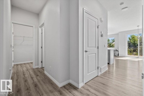 Wood-finish flooring throughout, white interior doors, and a sliding glass door with exterior access - 1014 Daniels Loop Sw, Edmonton, AB - Indoor Photo Showing Other Room