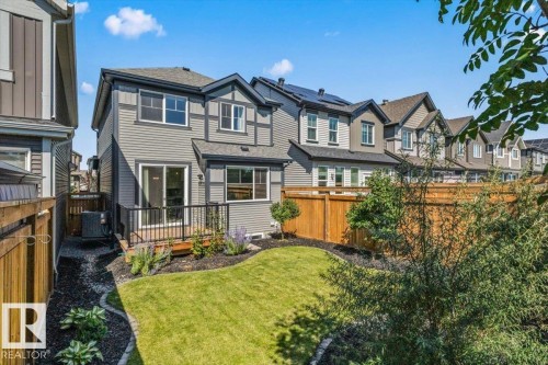 Rear exterior featuring a wooden deck, sliding glass doors, a manicured lawn, and a wooden privacy fence - 1014 Daniels Loop Sw, Edmonton, AB - Outdoor