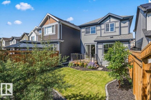 Landscaped backyard featuring a manicured lawn, wood deck, and wood privacy fence - 1014 Daniels Loop Sw, Edmonton, AB - Outdoor