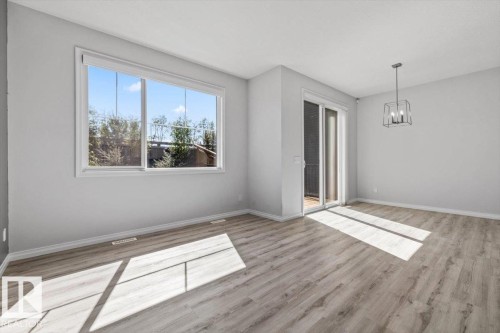 Recessed lighting, wood-finish flooring, sliding glass door, white trim, and a contemporary chandelier - 1014 Daniels Loop Sw, Edmonton, AB - Indoor Photo Showing Other Room