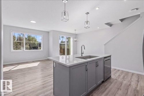 Spacious kitchen island with an undermount sink, stainless steel faucet, and dishwasher - 1014 Daniels Loop Sw, Edmonton, AB - Indoor Photo Showing Kitchen With Double Sink