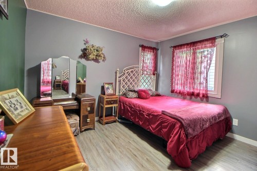 Wood-finish flooring with painted walls, ceiling light fixture, and two windows - #304 14004 26 St Nw, Edmonton, AB - Indoor Photo Showing Bedroom