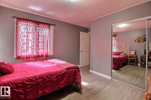Window with white trim, wood-finish flooring, and mirrored closet doors - #304 14004 26 St Nw, Edmonton, AB - Indoor Photo Showing Bedroom
