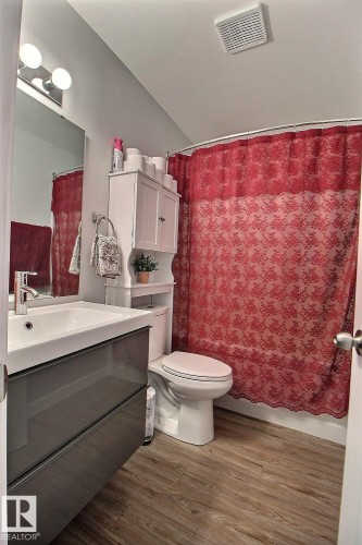 Bathroom featuring wood-finish flooring, a contemporary vanity with an integrated sink, a built-in over-toilet storage cabinet, and a ceiling-mounted exhaust fan - #304 14004 26 St Nw, Edmonton, AB - Indoor Photo Showing Bathroom