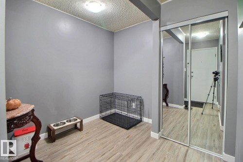 Wood-finish flooring with neutral wall paint and mirrored closet doors - #304 14004 26 St Nw, Edmonton, AB - Indoor Photo Showing Other Room