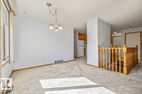 Carpeted room with a chandelier, wood-frame window, and a wood railing - 4427 Payne Avenue, Onoway, AB - Indoor Photo Showing Other Room