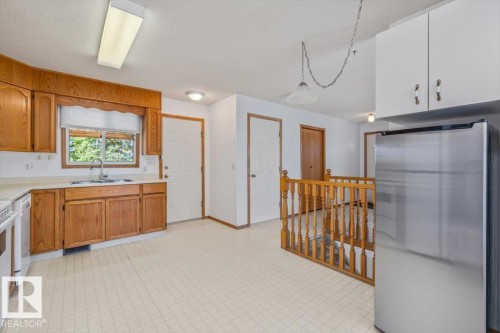Kitchen featuring wood cabinetry, light-toned countertop, stainless steel refrigerator, and tiled flooring - 4427 Payne Avenue, Onoway, AB - Indoor Photo Showing Kitchen