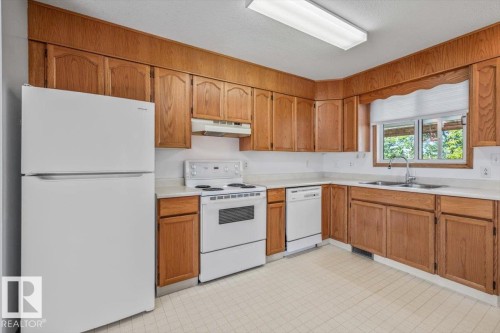 Kitchen featuring wood cabinetry, white countertops, a double basin sink, and a white appliance package - 4427 Payne Avenue, Onoway, AB - Indoor Photo Showing Kitchen With Double Sink