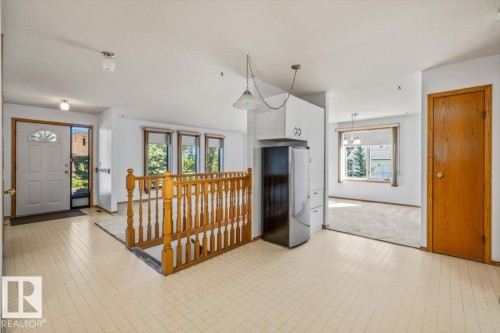 Cream-toned tiled flooring, white built-in cabinetry, and a wooden stair railing - 4427 Payne Avenue, Onoway, AB - Indoor Photo Showing Other Room