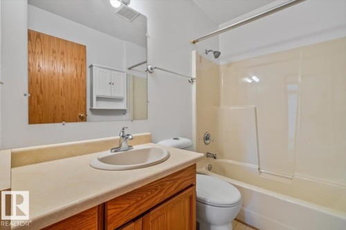 Bathroom featuring a wood-finish vanity with an integrated sink, a large mirror, a white medicine cabinet, and a shower-bathtub combination - 4427 Payne Avenue, Onoway, AB - Indoor Photo Showing Bathroom