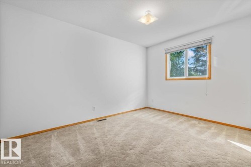 Neutral-toned carpeting with wood-finish trim and a single window featuring a wood-finish frame - 4427 Payne Avenue, Onoway, AB - Indoor Photo Showing Other Room