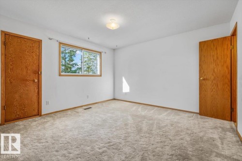 Carpeted flooring, white walls, wood-paneled doors, and a window with a wood frame - 4427 Payne Avenue, Onoway, AB - Indoor Photo Showing Other Room