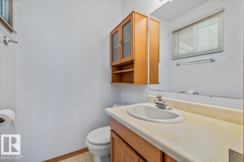 Light-toned wood vanity with an integrated sink, coordinating wall-mounted storage cabinet, and a large mirror - 4427 Payne Avenue, Onoway, AB - Indoor Photo Showing Bathroom