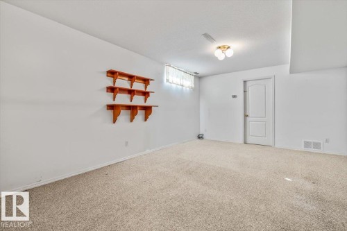 Recessed ceiling light fixture, white interior door, wall-mounted wooden shelving, and neutral carpet flooring - 4427 Payne Avenue, Onoway, AB - Indoor Photo Showing Other Room