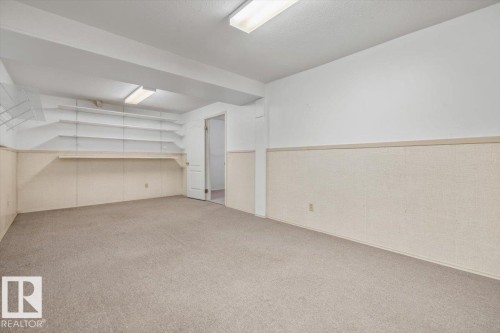 Wall-to-wall carpeting, built-in shelving, white walls, and a light-colored wainscoting - 4427 Payne Avenue, Onoway, AB - Indoor Photo Showing Other Room