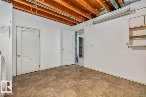 Exposed wood ceiling beams, neutral-toned floor tiling, white walls, and built-in shelving - 4427 Payne Avenue, Onoway, AB - Indoor