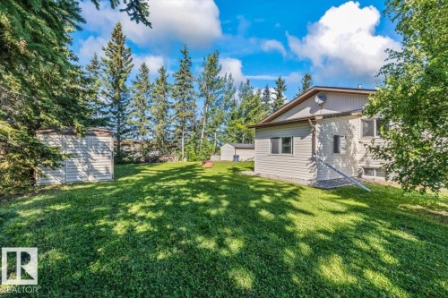 Expansive green space featuring mature trees and two accessory sheds - 4427 Payne Avenue, Onoway, AB - Outdoor