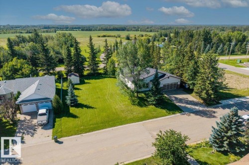 Expansive green space with mature trees, paved driveway, and detached storage shed - 4427 Payne Avenue, Onoway, AB - Outdoor With View