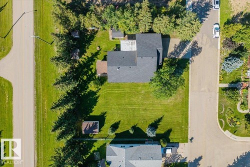 Expansive property featuring a paved road, paved driveway, mature trees, and a well-maintained lawn - 4427 Payne Avenue, Onoway, AB - Outdoor With View