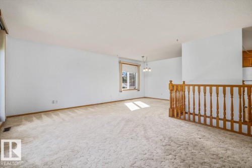 Neutral wall finishes, light-toned carpeting, and a built-in chandelier - 4427 Payne Avenue, Onoway, AB - Indoor Photo Showing Other Room