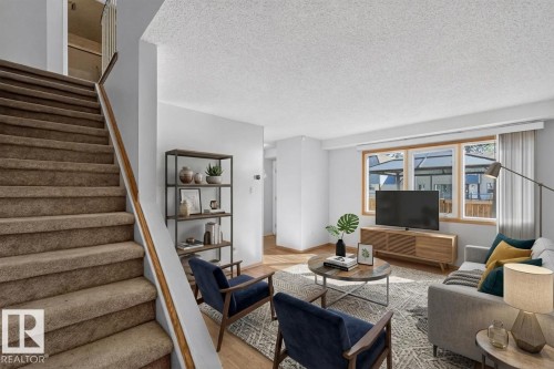 Carpeted staircase with wood handrail, wood-finish flooring, and a large window with wood trim - 23 Willowdale Place Nw, Edmonton, AB 