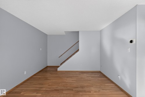 Hardwood flooring throughout, light gray wall finishes, and a staircase with natural wood handrails - 23 Willowdale Place Nw, Edmonton, AB 