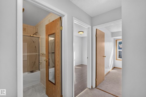 Bathroom with tiled walls and flooring, tub with shower, and glass enclosure - 23 Willowdale Place Nw, Edmonton, AB 