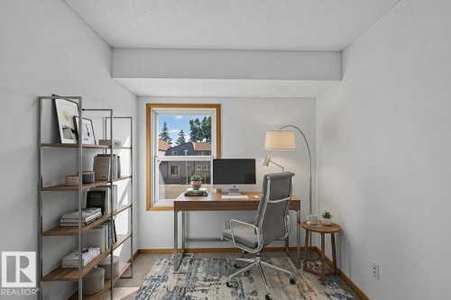 Bright interior space featuring wood-finish flooring, a double-hung window with wood trim, and painted walls - 23 Willowdale Place Nw, Edmonton, AB 