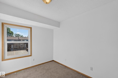 White painted walls, wood-finish window trim, and a flush mount ceiling light - 23 Willowdale Place Nw, Edmonton, AB 