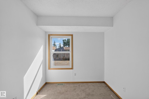 Carpeted flooring with wood-finish trim and a single window with wood-finish casing - 23 Willowdale Place Nw, Edmonton, AB 