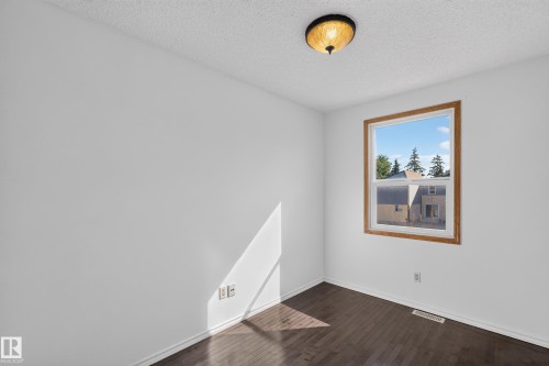 Wood-finish flooring, single window with wood trim, ceiling-mounted light fixture, and white wall finishes - 23 Willowdale Place Nw, Edmonton, AB 