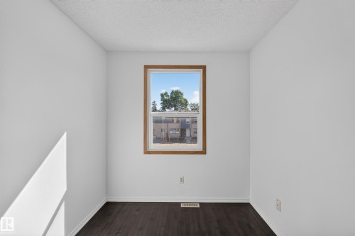 Warm-toned window trim, dark wood-finish flooring, white painted walls, and a textured ceiling - 23 Willowdale Place Nw, Edmonton, AB 