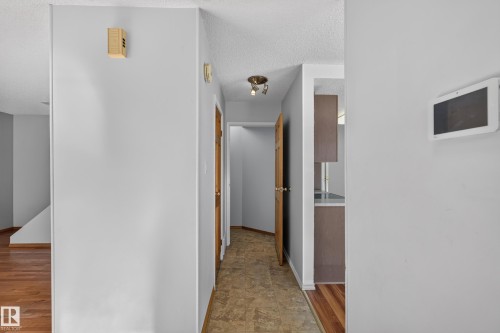 Hallway with light gray walls, wood-finish doors, and track lighting - 23 Willowdale Place Nw, Edmonton, AB 
