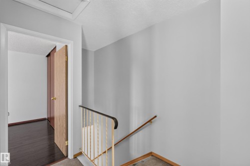 Doorway with light wood-finish door, dark wood-finish flooring, and closet with sliding panels - 23 Willowdale Place Nw, Edmonton, AB 