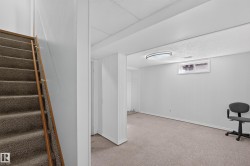 Carpeted staircase with wood handrail, leading to a carpeted room with a flush-mount ceiling light fixture and a window - 