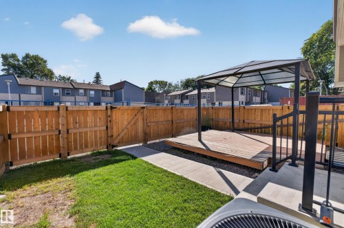 Fenced backyard featuring a wooden deck with a gazebo, a concrete pathway, and a grassy area - 23 Willowdale Place Nw, Edmonton, AB 