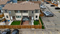 Townhouse exterior featuring a neutral stucco and siding facade, private fenced yard, and dedicated parking spaces - 