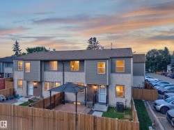 Two-story multi-unit dwelling with gray siding and stucco exterior, featuring a private fenced yard with a wood-finish deck and a gazebo - 