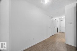 Hallway featuring wood-finish flooring, white walls, and multiple panel doors - 