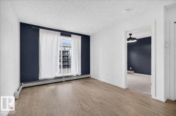Spacious room featuring wood-finish flooring, a contemporary accent wall, and a sliding glass door leading to a balcony - 