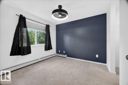 Bedroom featuring light carpeting, a window with exterior greenery, and a contemporary ceiling fixture - 