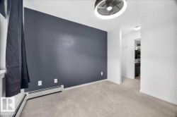 Room featuring a modern semi-flush mount ceiling fixture, soft neutral-toned carpeting, a window with dark drapery, a baseboard heater, and a contrasting accent wall - 