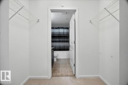 Walk-through closet featuring wire shelving and carpet flooring, leading to a bathroom with tile flooring, a white toilet, and a white bathtub - 