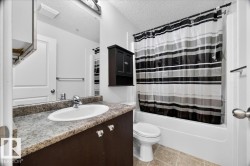 Bathroom featuring a built-in vanity with a stone-finish countertop, undermount sink, and dark wood cabinetry - 