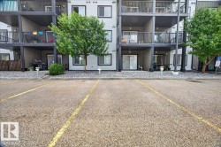 Multi-level residential building featuring light grey siding with dark trim, private balconies, and ground-level patios - 