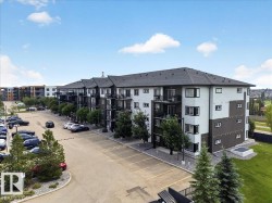 Modern multi-story residential building featuring a dark shingle roof, white and dark gray exterior siding, and multiple private balconies with black railings - 