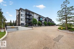 Contemporary multi-story building featuring individual balconies with dark railings, a light-colored exterior facade, and a subterranean parking garage entrance - 